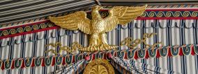 Goldenes Vogel Emblem vor edlem Stoff