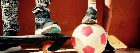 Beine von zwei Jungen mit Skateboard und Fußball